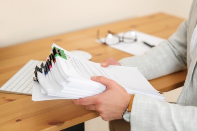 Businessman with documents at wooden table in office, closeup