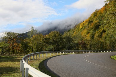 Photo of Picturesque view of empty road near trees with sign Chevron Left in mountains