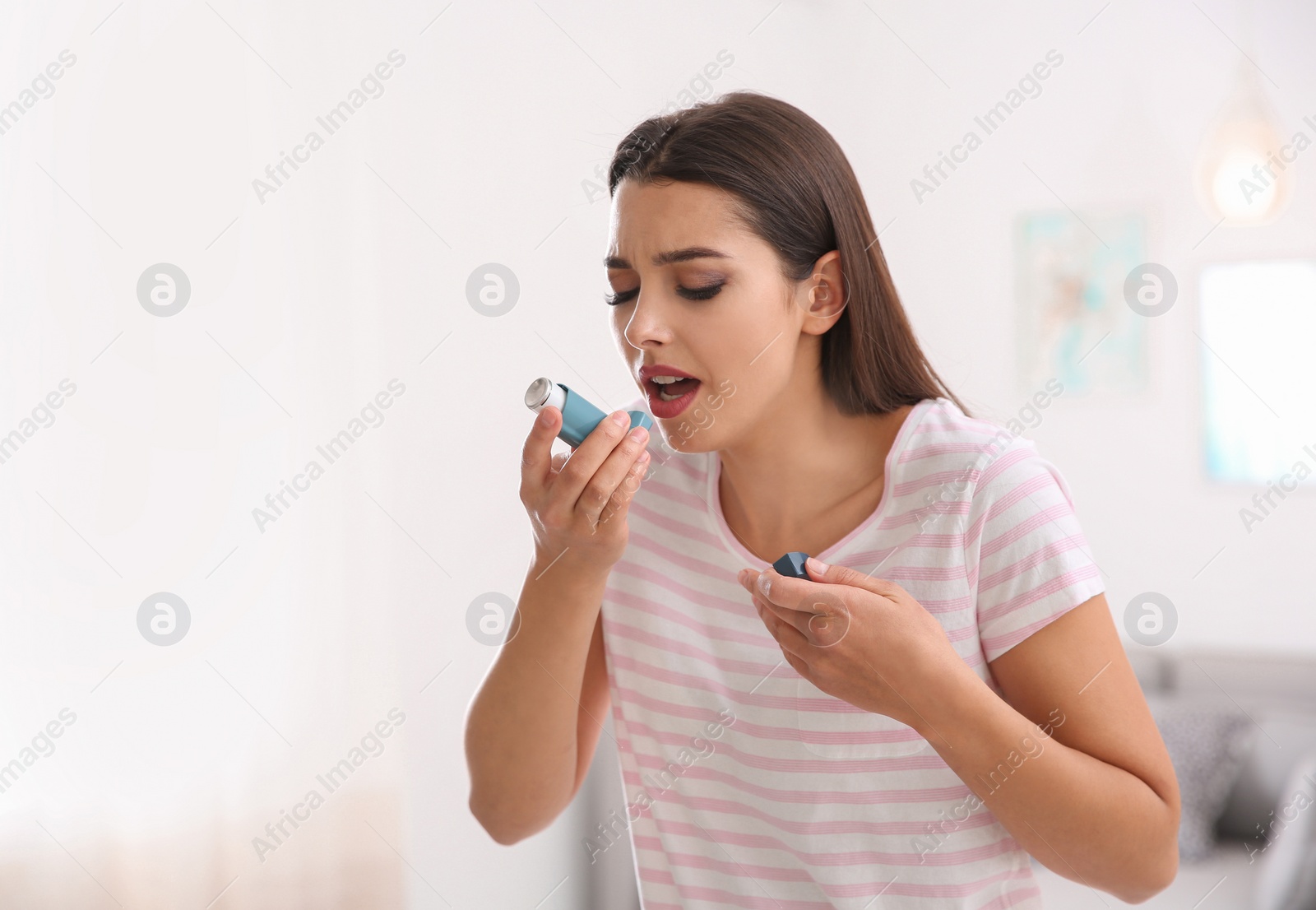 Photo of Woman with asthma inhaler in light room