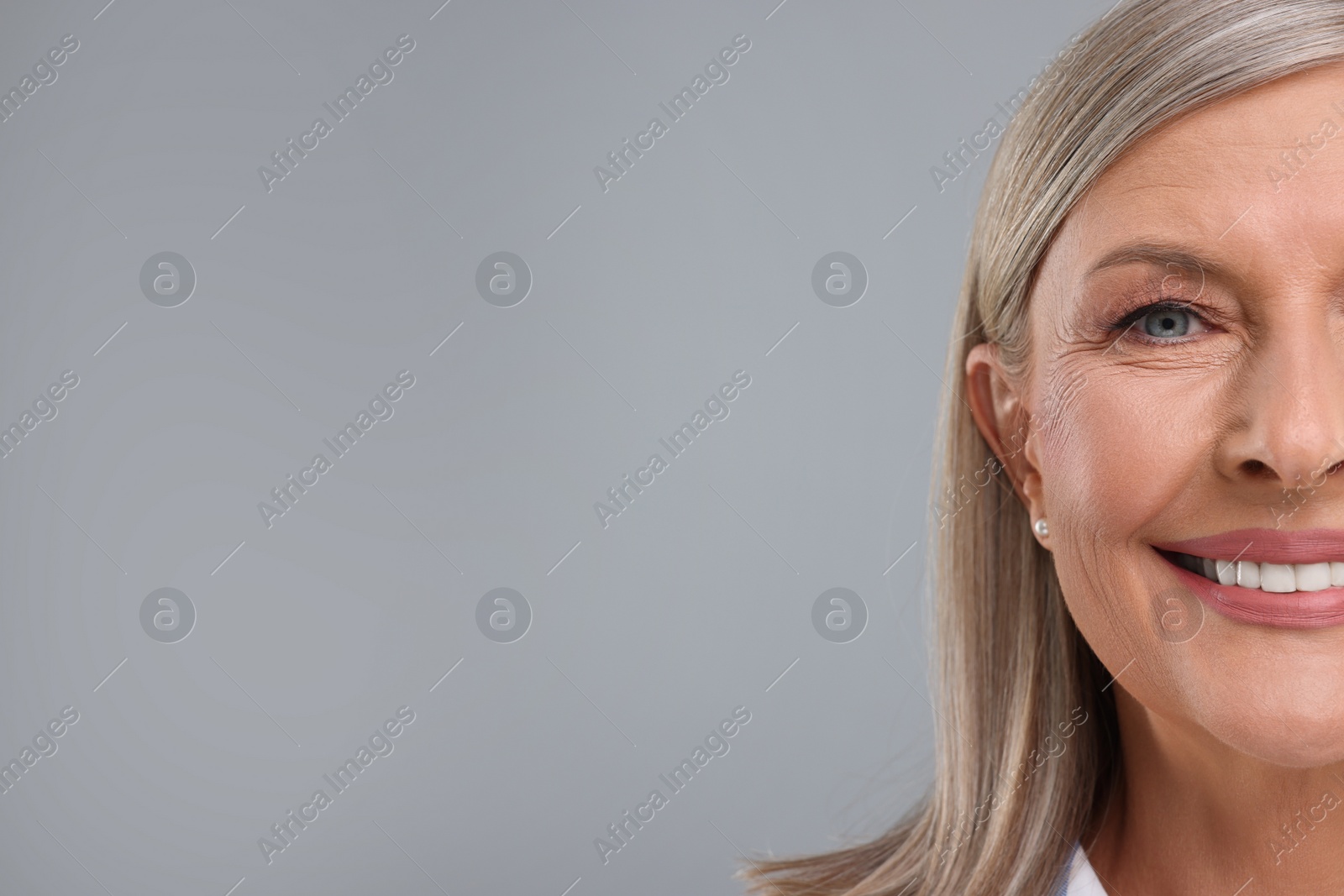 Photo of Portrait of beautiful middle aged woman on light grey background, closeup. Space for text