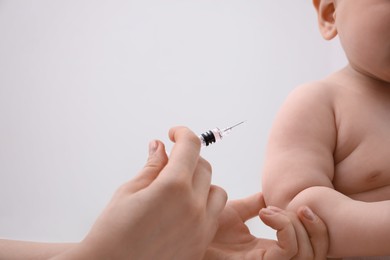 Doctor vaccinating baby against light background, closeup. Health care
