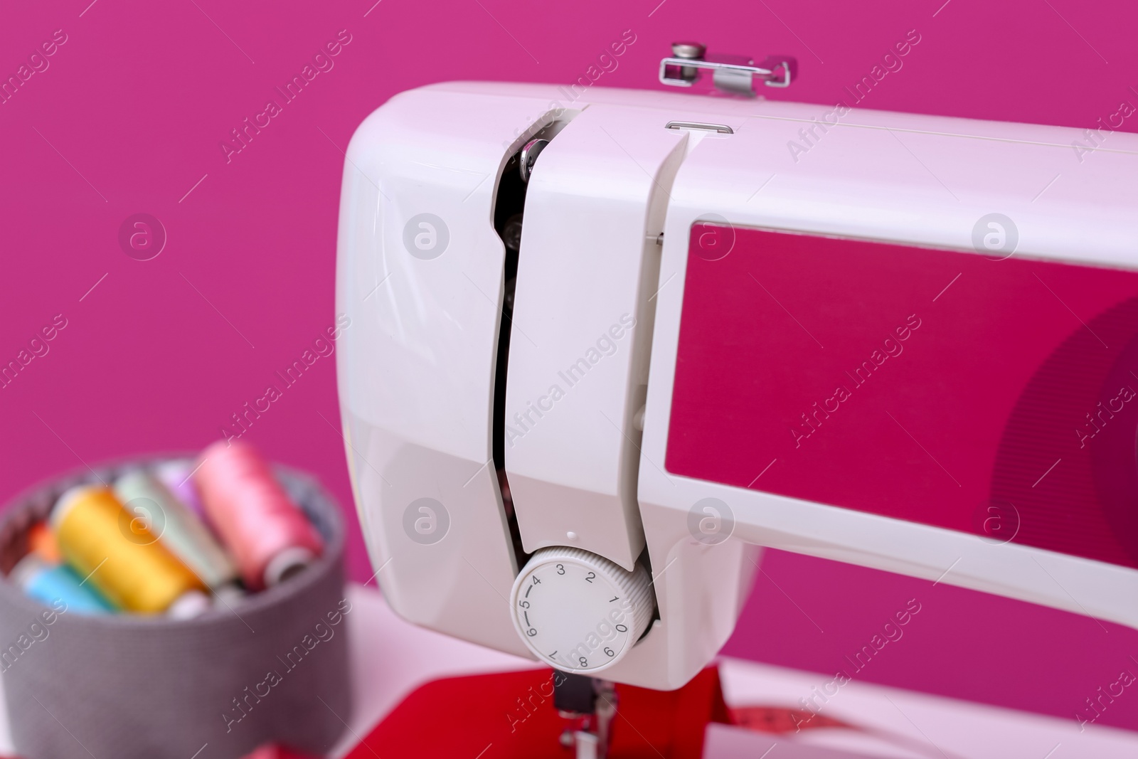 Photo of Modern sewing machine on color background, closeup