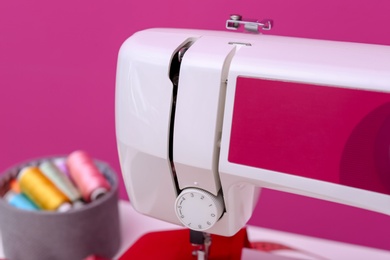 Modern sewing machine on color background, closeup