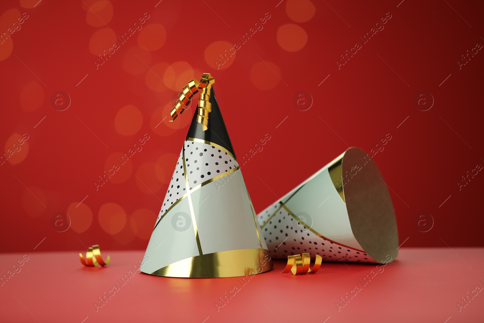 Photo of Beautiful party hats and serpentine streamers on red background