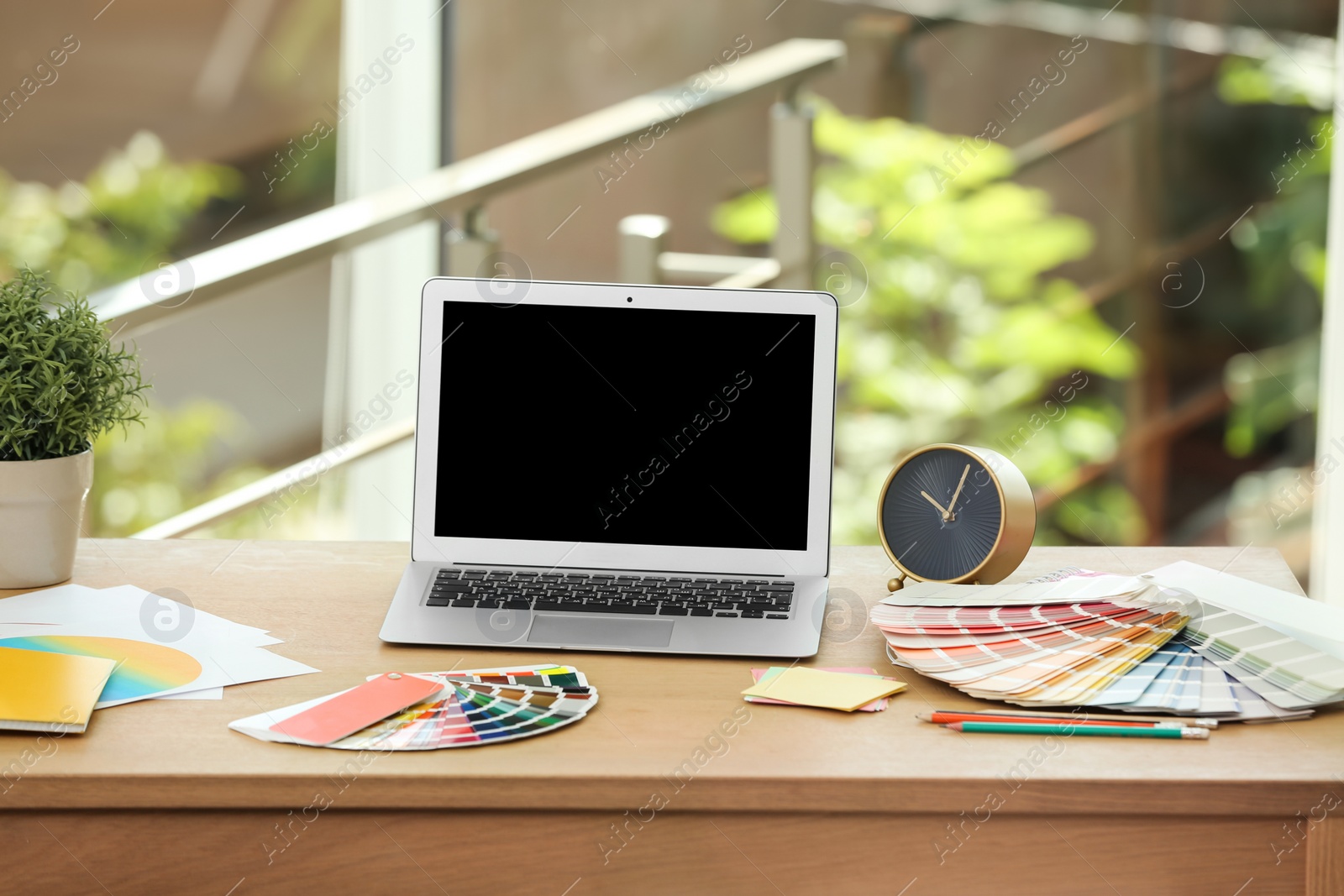 Photo of Designer's workplace with laptop and paint color palette samples on table