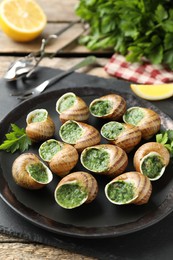 Delicious cooked snails with parsley on table, closeup