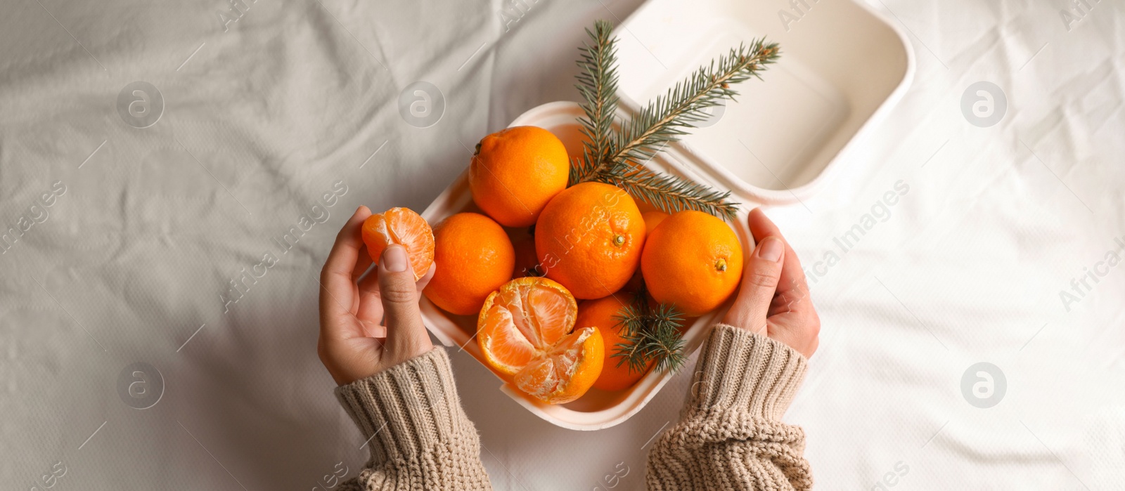 Photo of Woman with delicious ripe tangerines on white bedsheet, top view