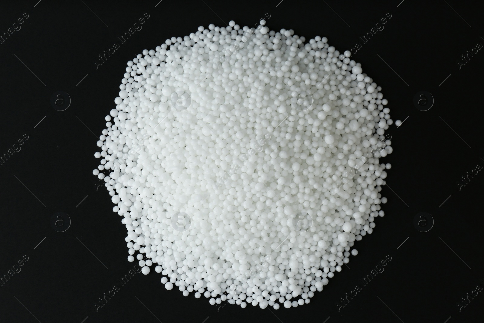 Photo of Pellets of ammonium nitrate on black background, flat lay. Mineral fertilizer