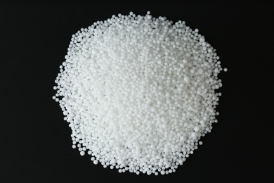 Photo of Pellets of ammonium nitrate on black background, flat lay. Mineral fertilizer