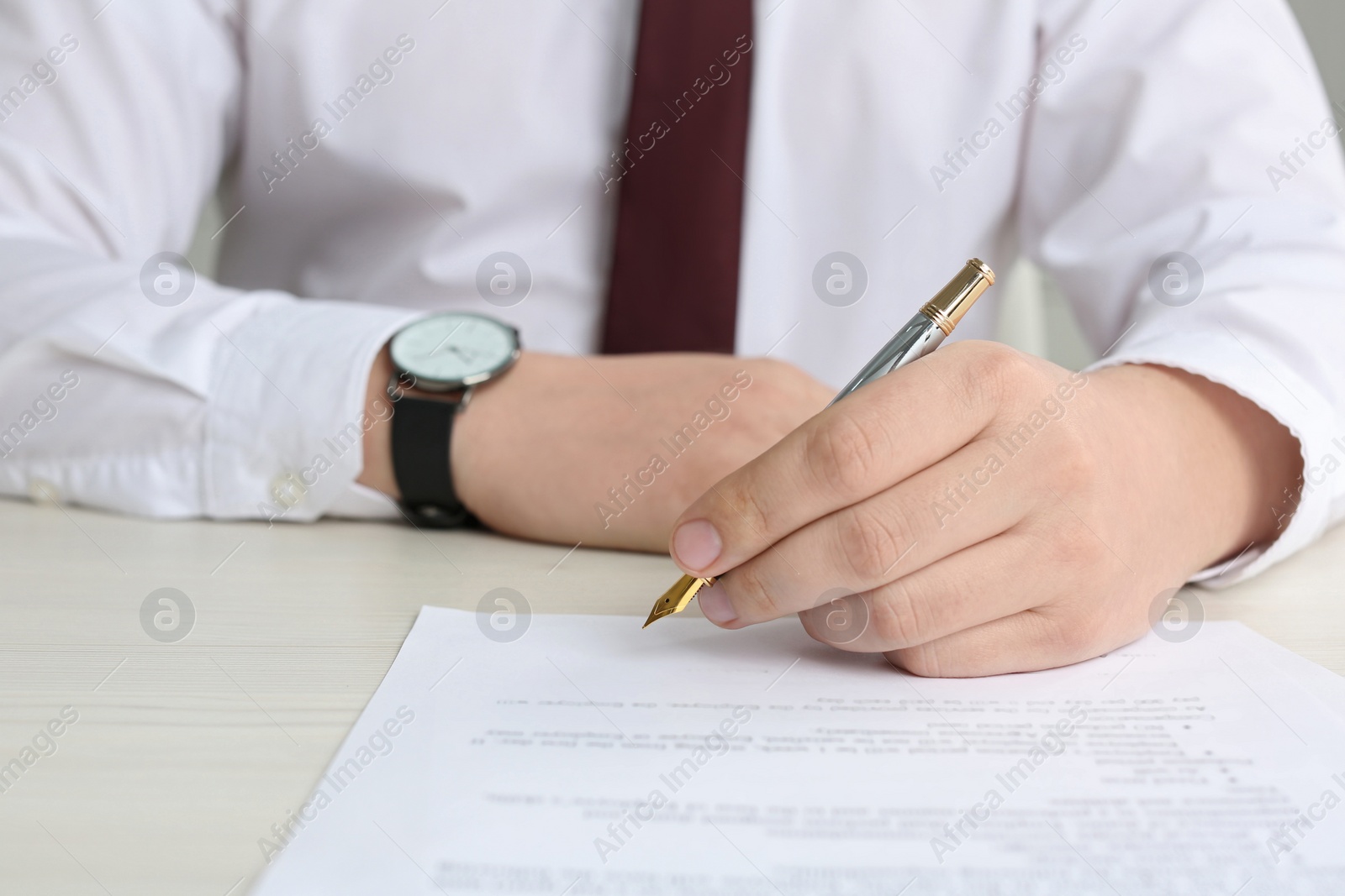 Photo of Notary signing document at wooden table, closeup