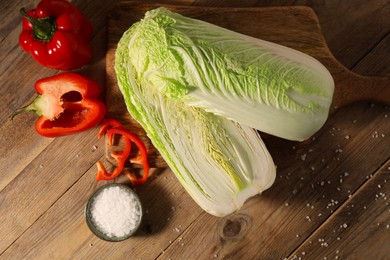 Fresh Chinese cabbages, bell peppers and salt on wooden table, flat lay