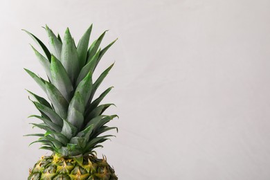 Photo of Delicious ripe pineapple on light grey background, closeup. Space for text