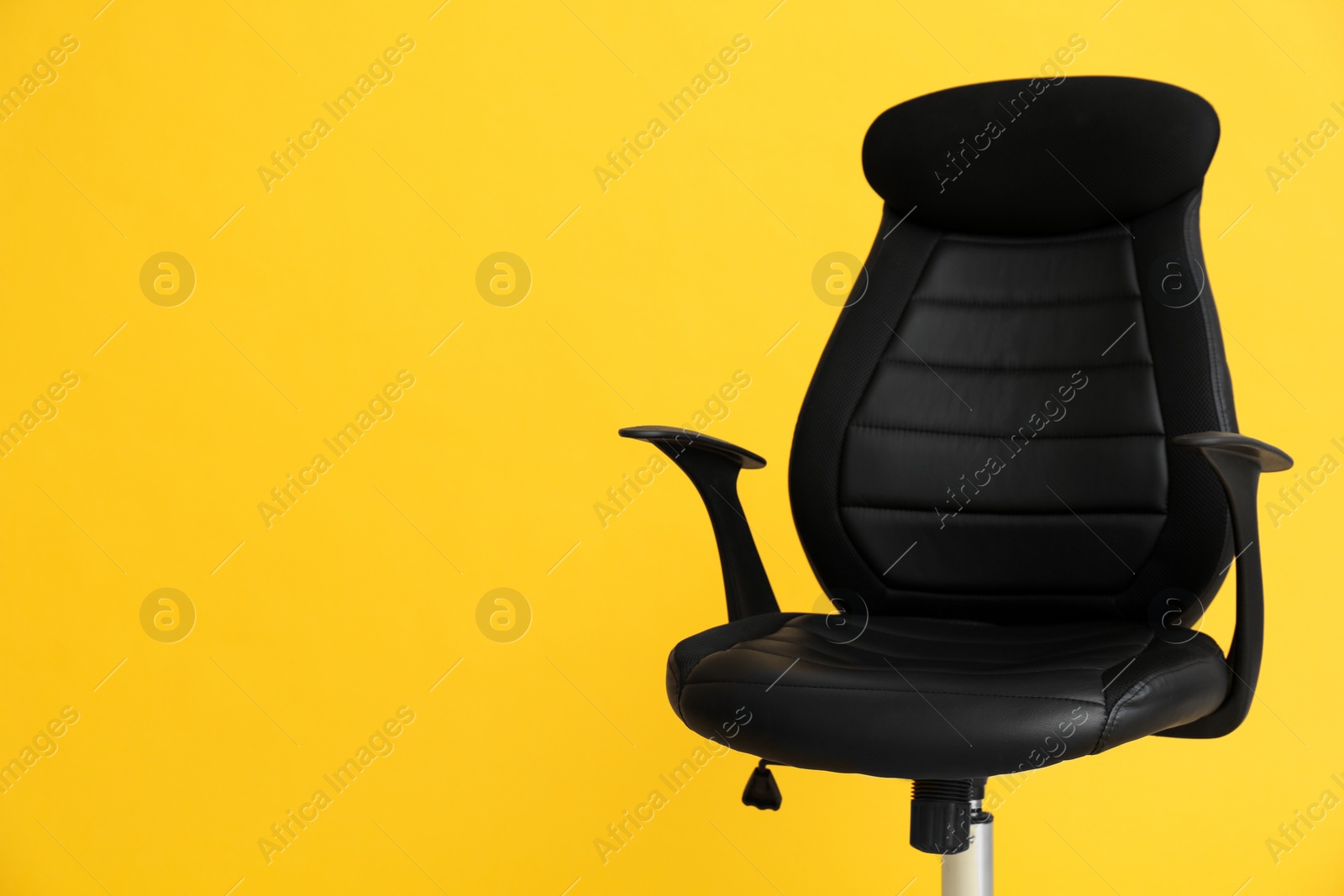 Photo of Modern office chair on yellow background. Space for text