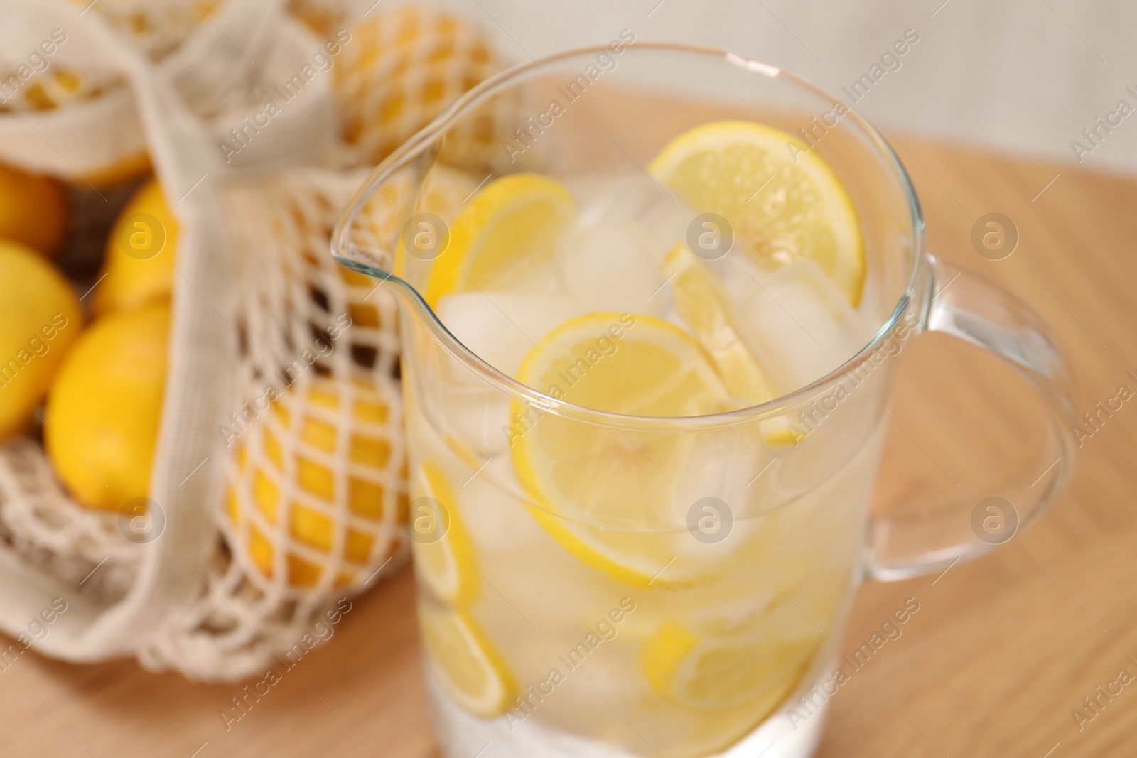 Photo of Freshly made lemonade in jug on wooden table indoors, closeup