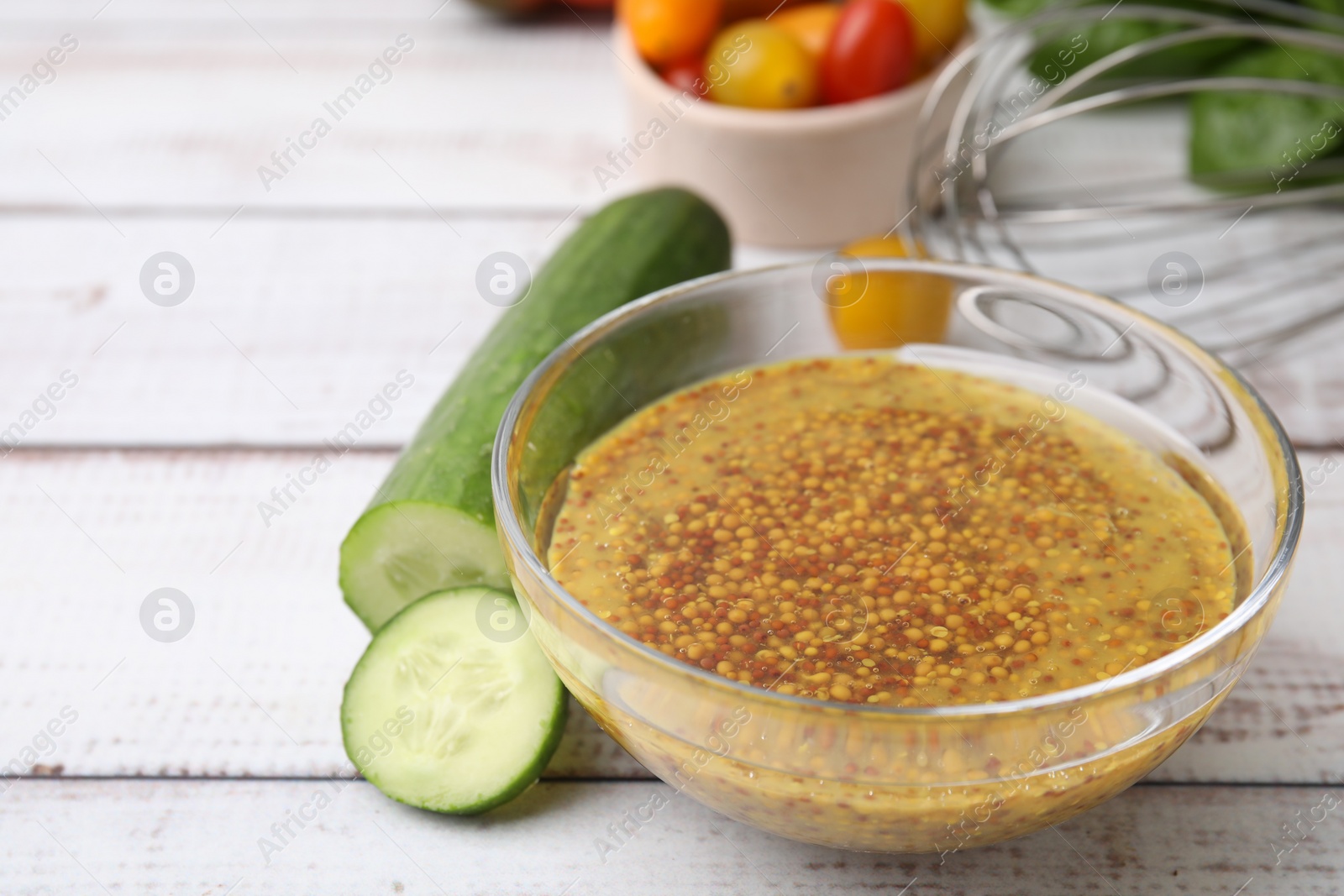 Photo of Tasty vinegar based sauce (Vinaigrette) in bowl and cucumber on wooden rustic table, closeup. Space for text