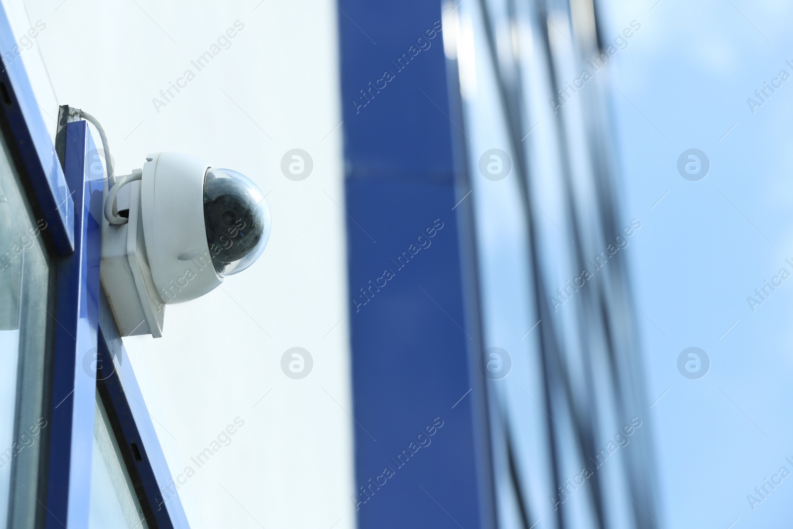 Photo of Modern CCTV security camera on building wall outdoors. Space for text