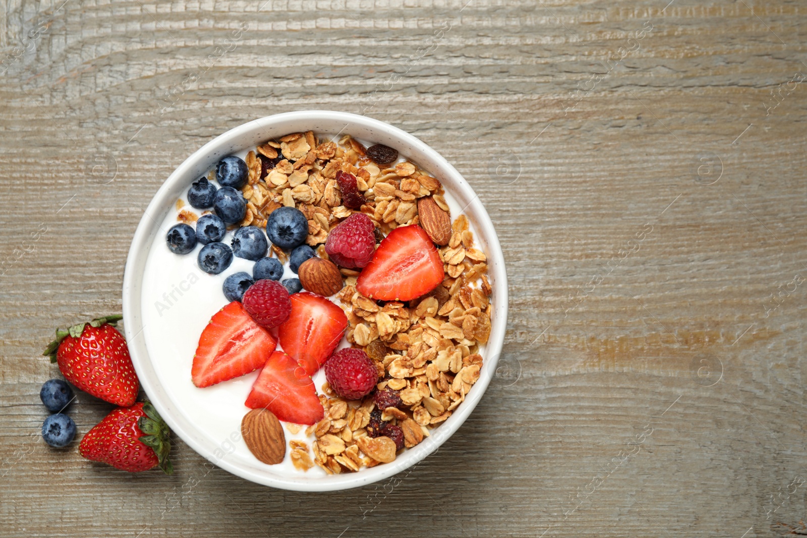 Photo of Tasty homemade granola served on wooden table, flat lay with space for text. Healthy breakfast