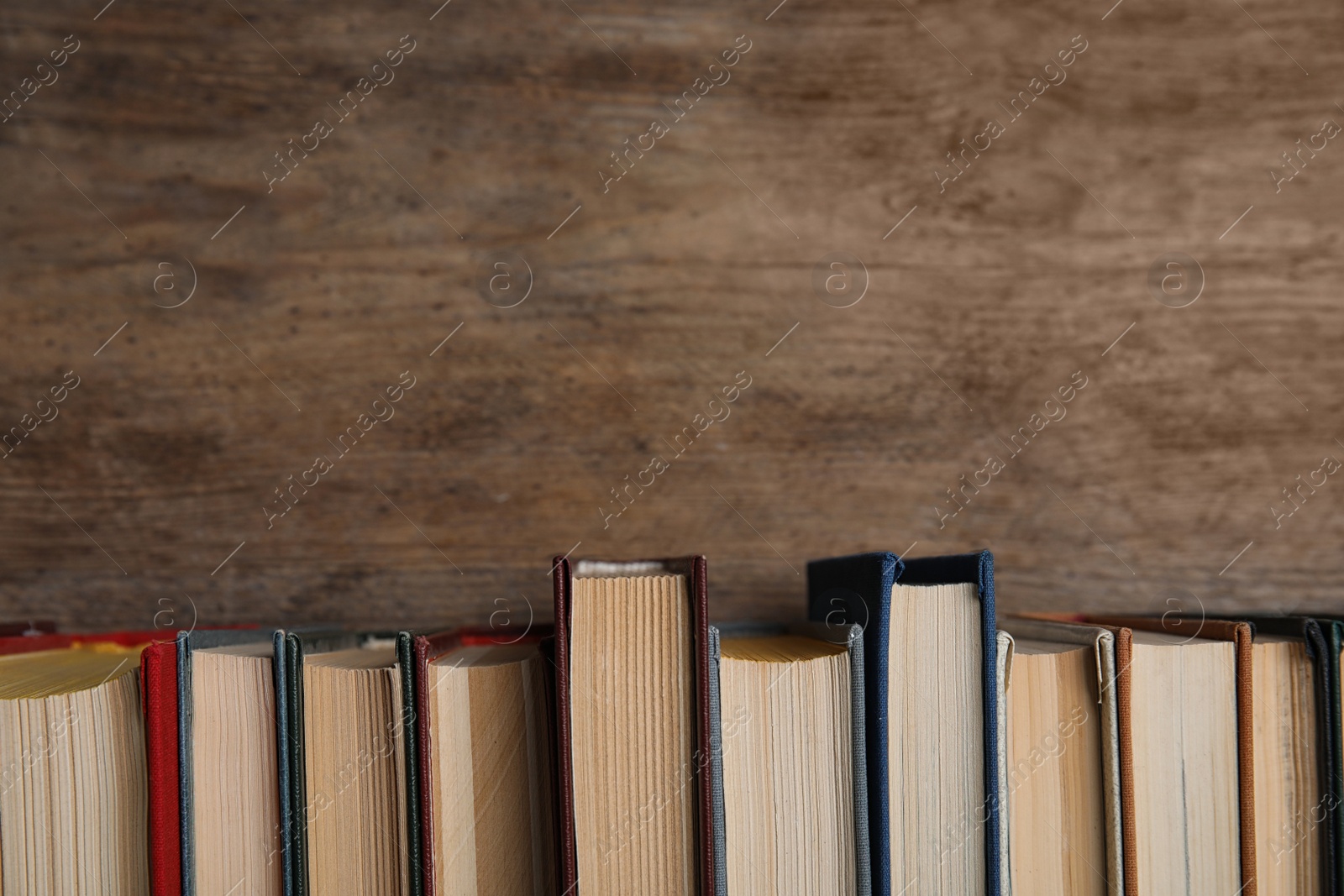 Photo of Stack of hardcover books on wooden background. Space for text