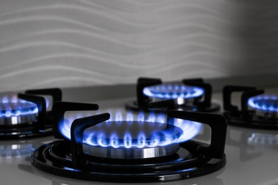 Photo of Modern gas cooktop with burning blue flames in kitchen