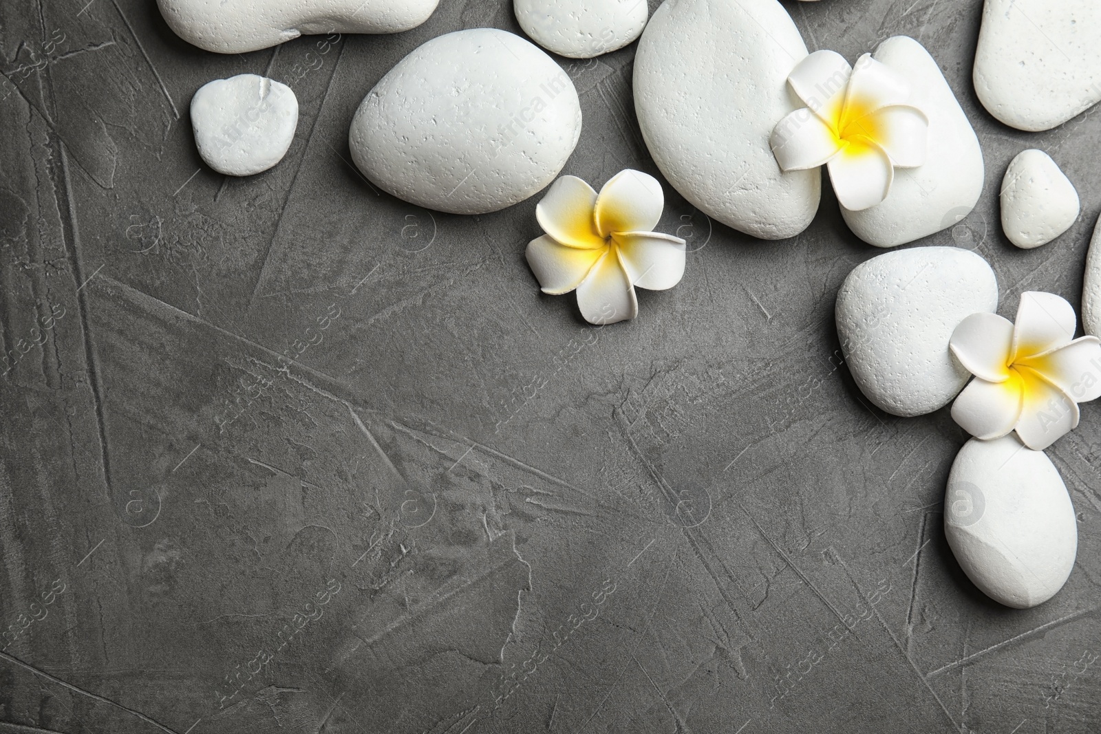 Photo of Zen stones and exotic flowers on dark background, top view with space for text