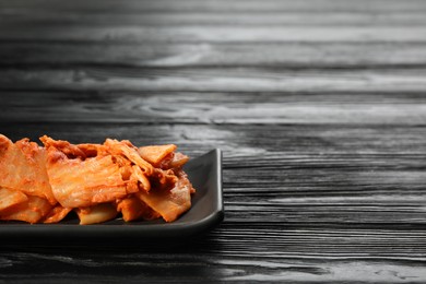 Delicious kimchi with Chinese cabbage on black wooden table, space for text