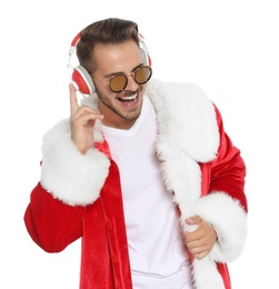 Young man in Santa costume listening to Christmas music on white background