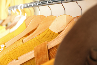 Photo of Different styling clothes on wooden hangers in wardrobe, closeup. Fashion blogger