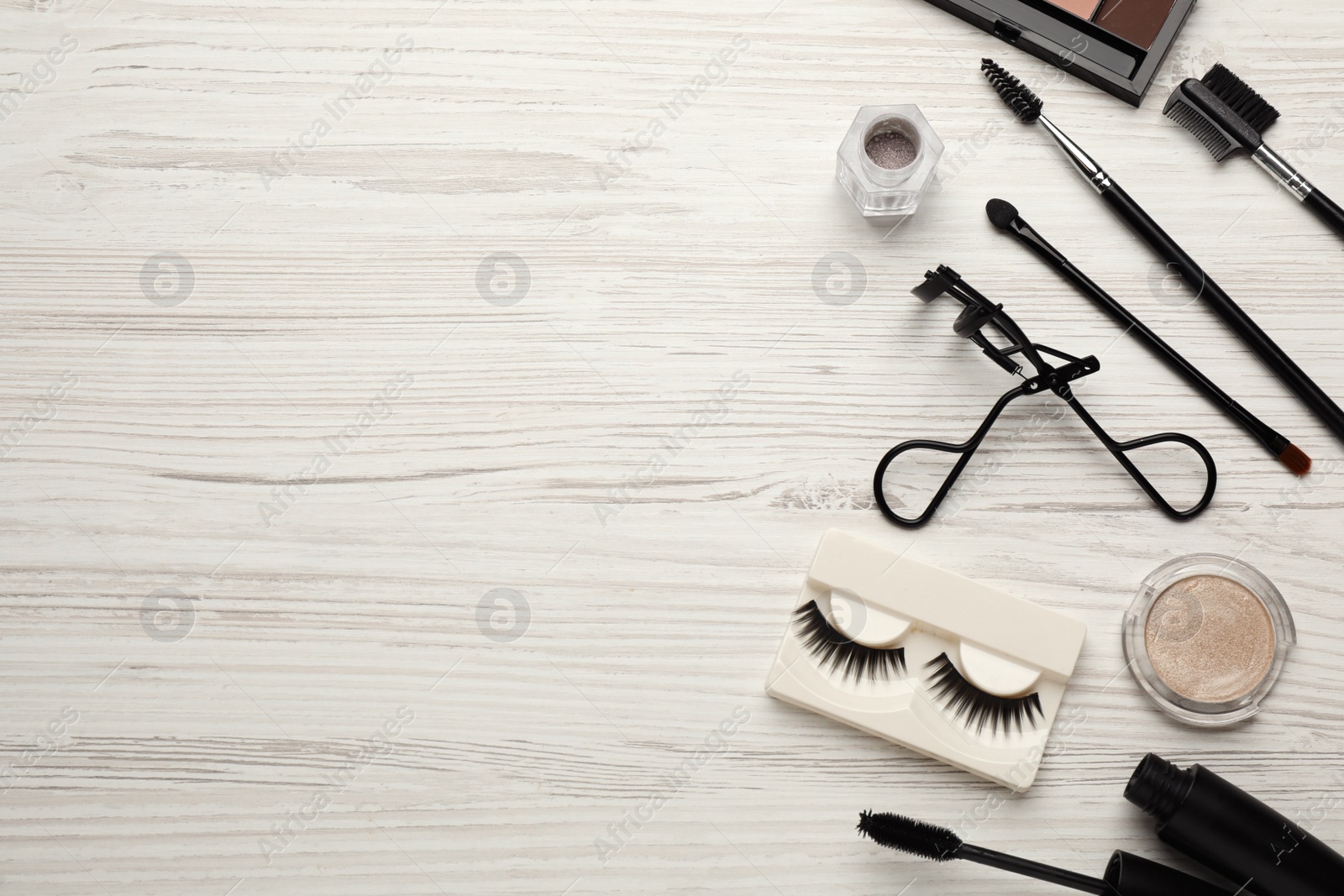 Photo of Flat lay composition with eyelash curler, makeup products and accessories on white wooden table. Space for text