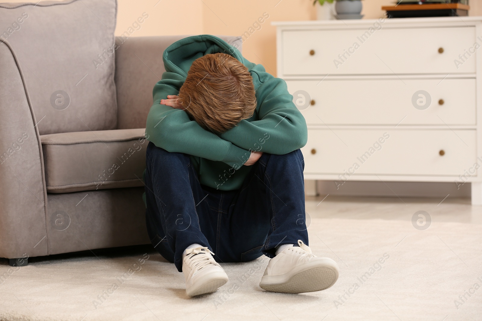 Photo of Upset teenage boy sitting alone in room