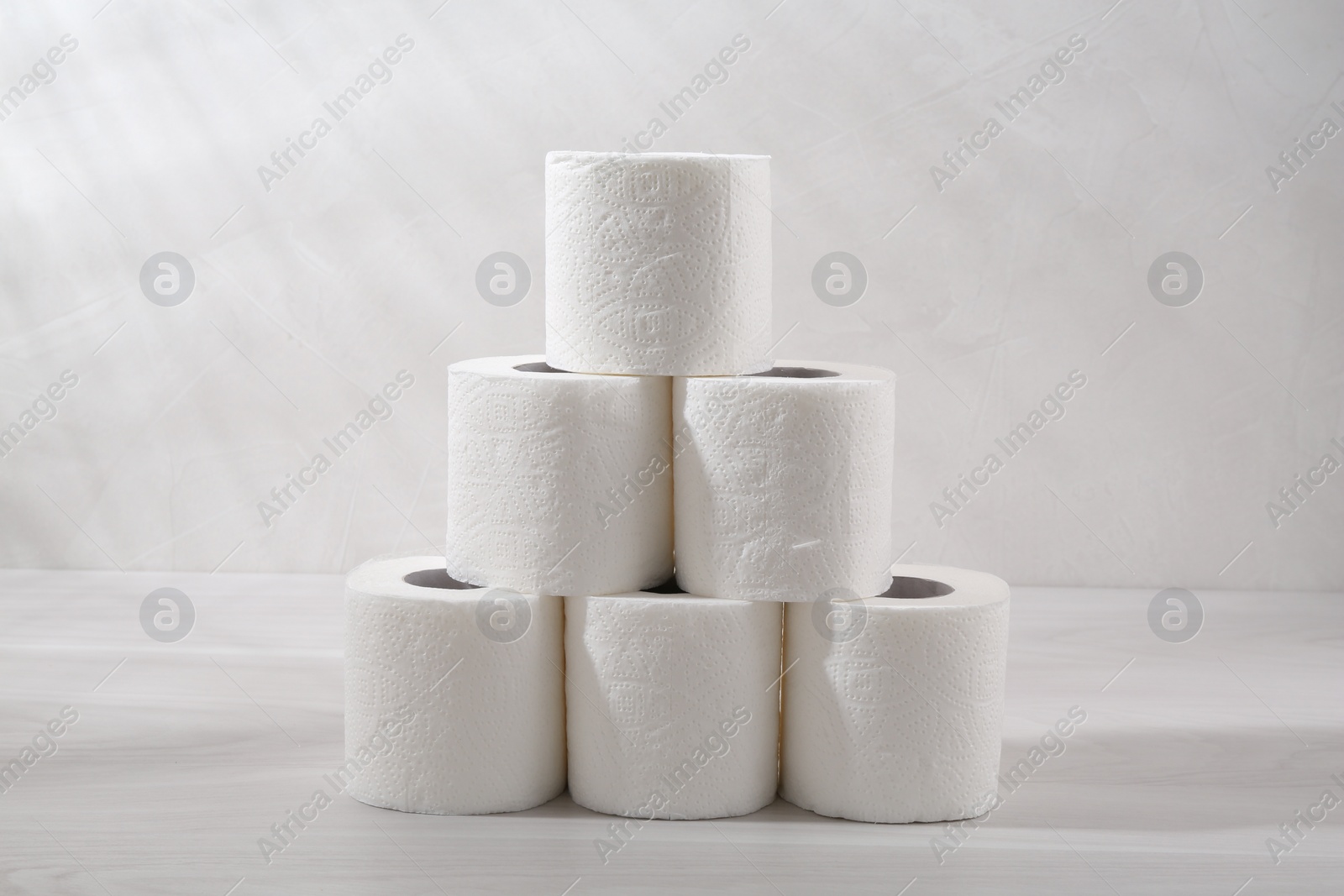 Photo of Pyramid of toilet paper rolls on white wooden table