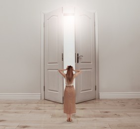 Image of Woman standing in front of open door, back view