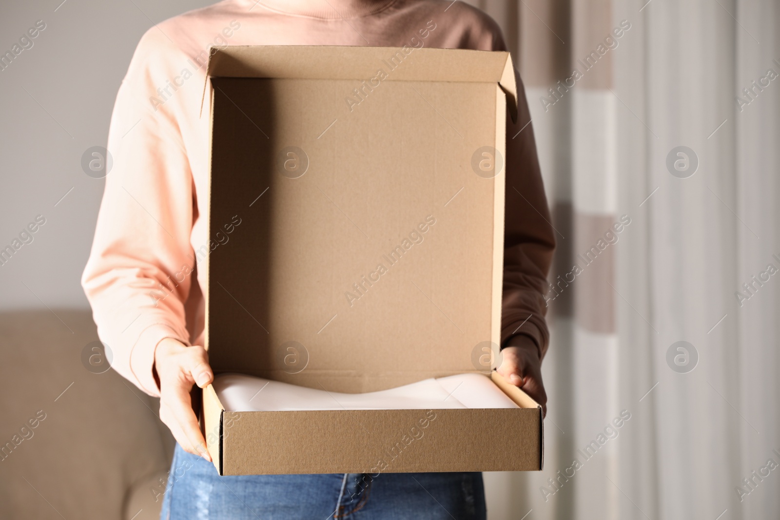 Photo of Woman with open cardboard box at home, closeup