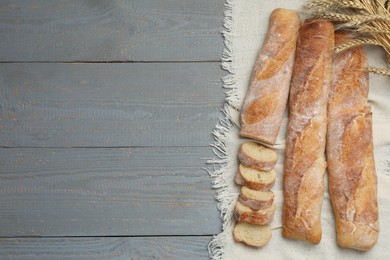 Photo of Delicious French baguettes on grey wooden table, top view. Space for text