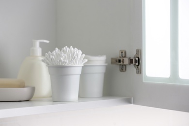 Photo of Cotton buds and different toiletries on shelf indoors