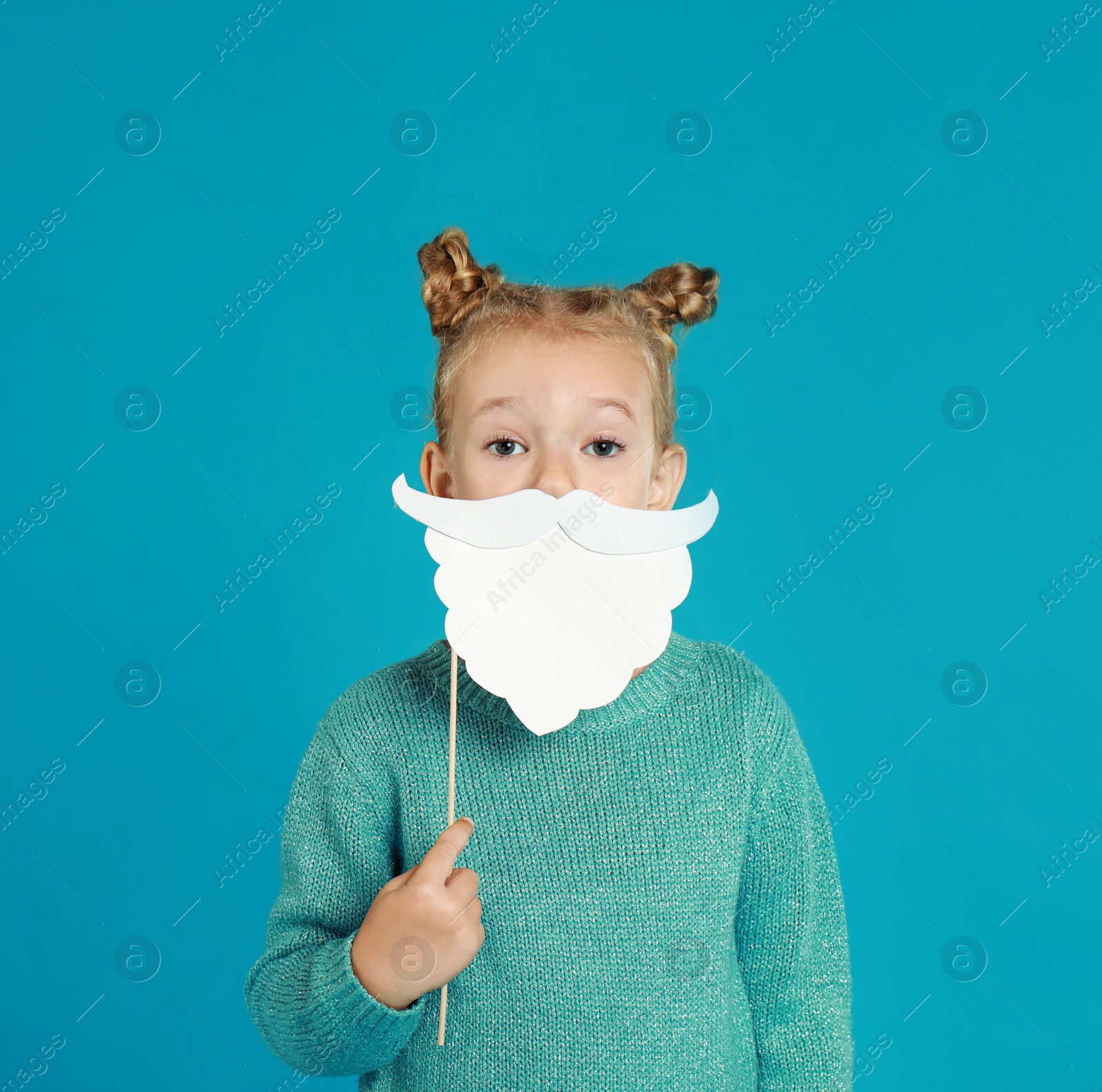 Image of Cute little girl with Santa beard prop on light blue background. Christmas celebration