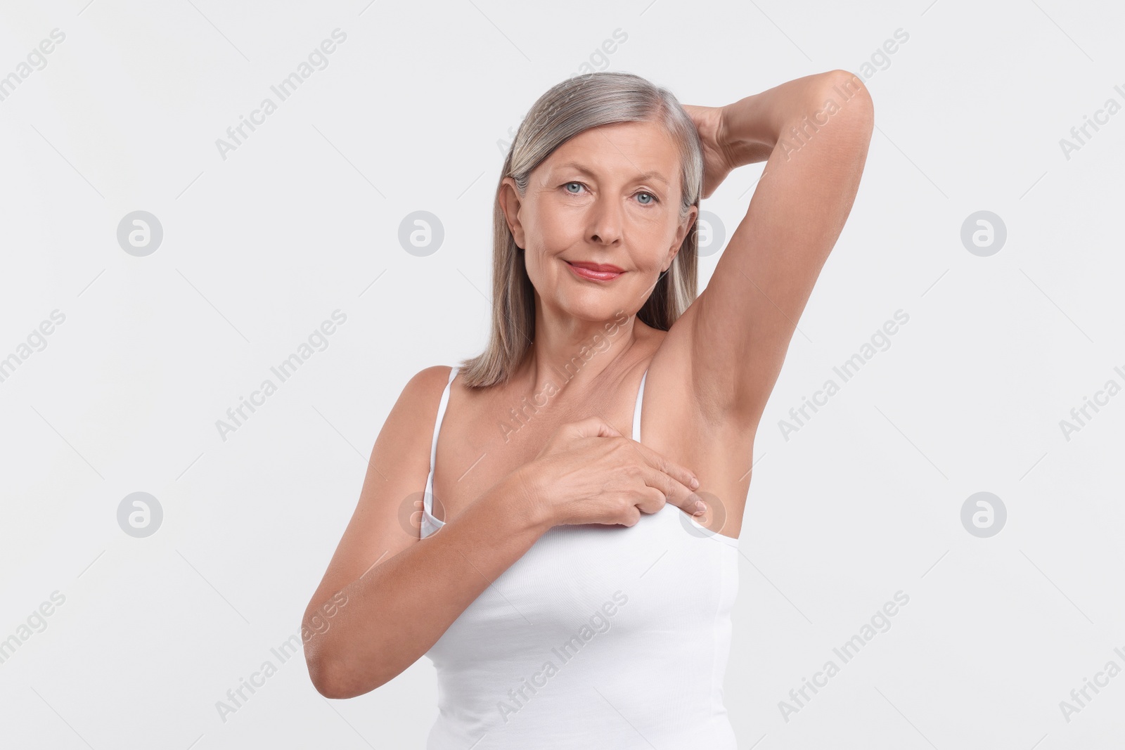 Photo of Beautiful senior woman doing breast self-examination on white background