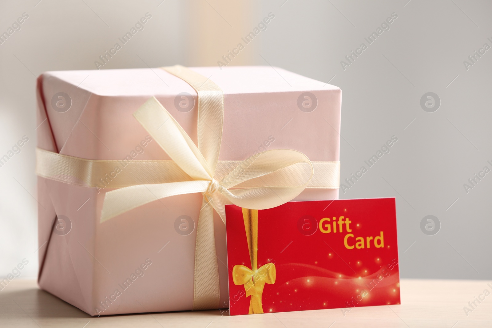 Photo of Gift card and present on table against blurred background