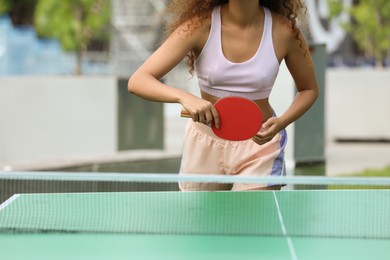 Photo of African-American woman playing ping pong outdoors, closeup