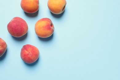 Photo of Many whole fresh ripe peaches on light blue background, flat lay. Space for text