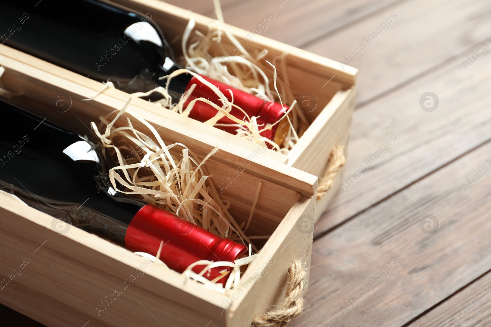 Photo of Bottles with delicious red wine in boxes on wooden background