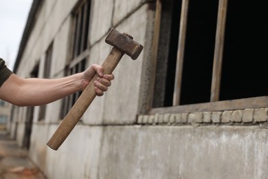 Photo of Man with sledgehammer near old building outdoors, closeup. Space for text