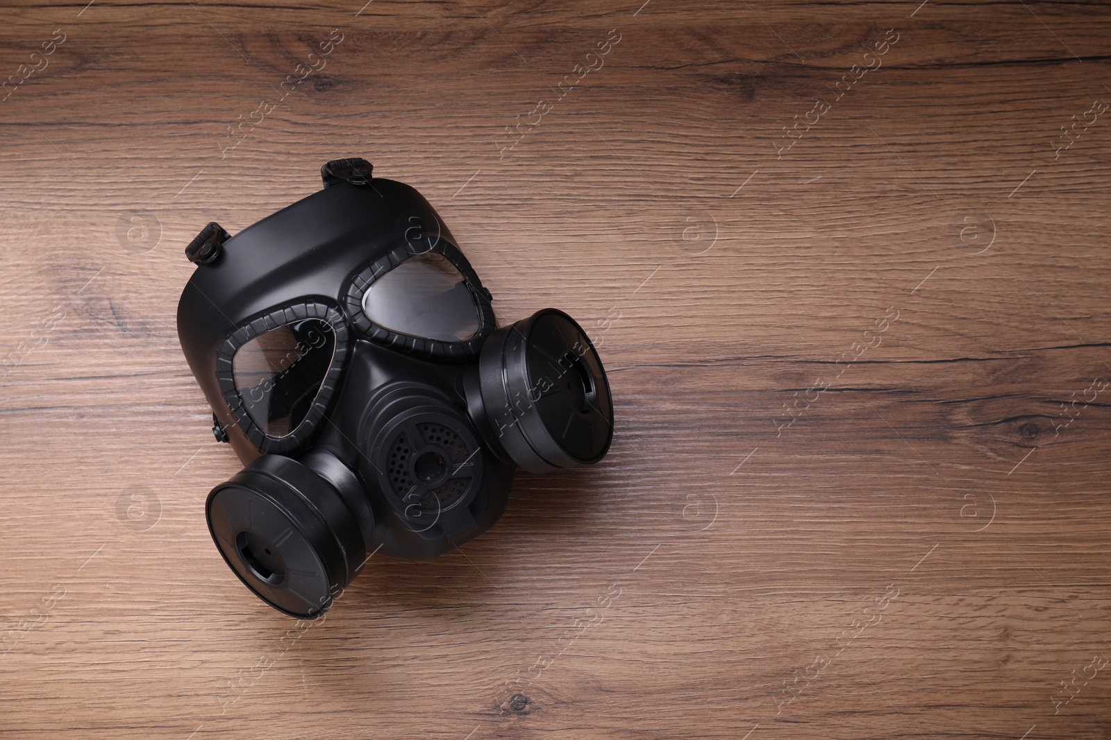 Photo of One gas mask on wooden background, top view. Space for text