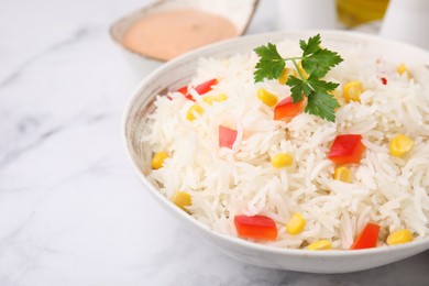 Photo of Bowl of delicious rice with vegetables and parsley on light table, closeup