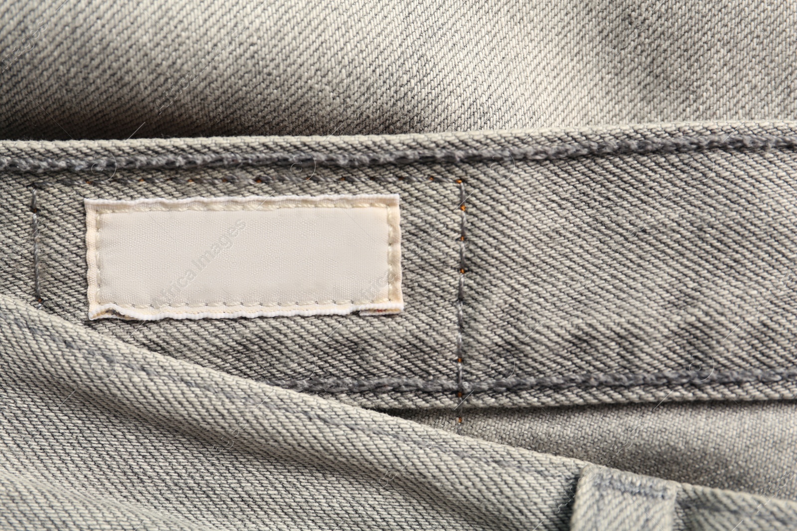 Photo of Blank clothing label on grey jeans, top view