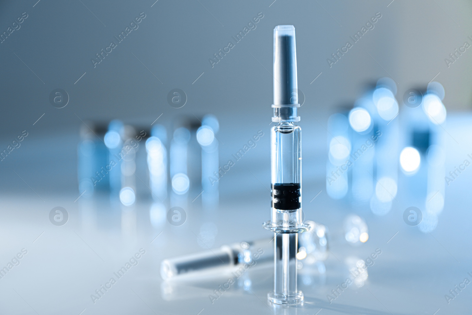 Photo of Syringes with COVID-19 vaccine on light table, space for text