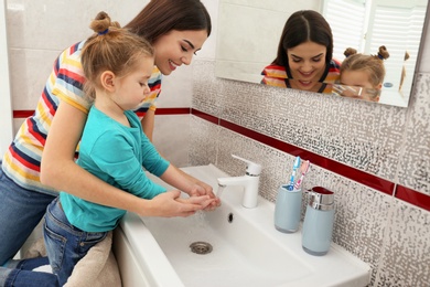 Photo of Happy mother and daughter washing hands in bathroom at home