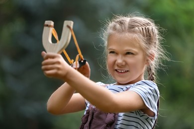Photo of Little girl playing with slingshot in park