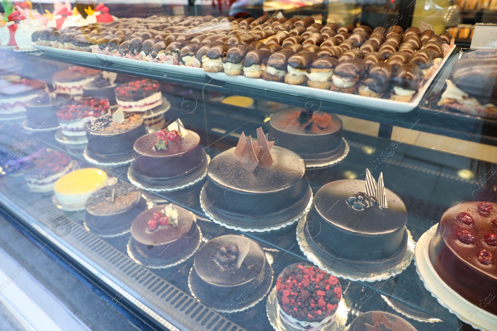 Photo of Different delicious cakes on display in cafe, view through window