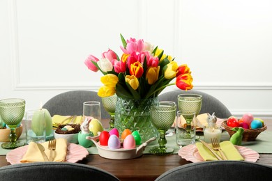 Photo of Easter celebration. Festive table setting with beautiful flowers and painted eggs