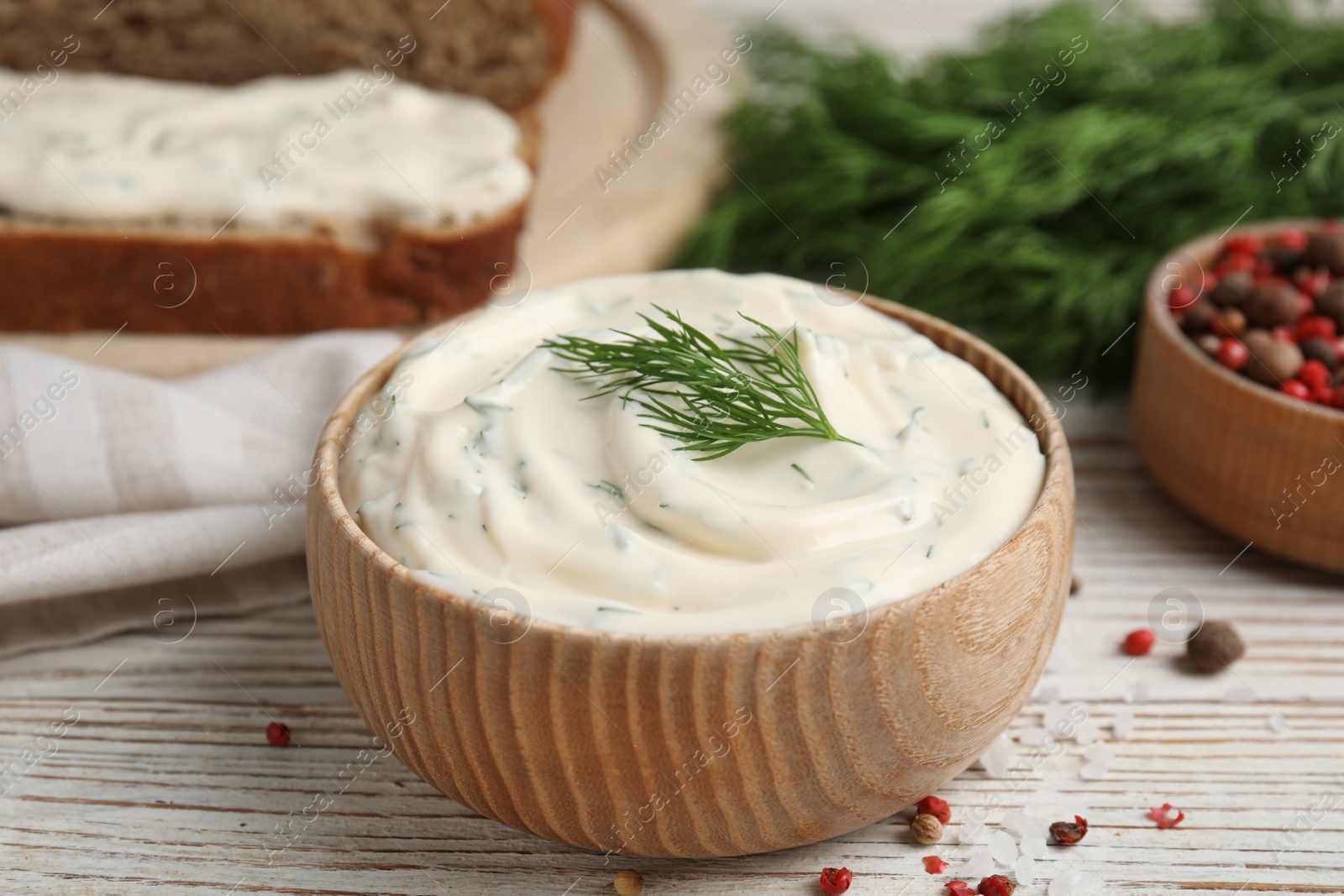 Photo of Tasty creamy dill sauce in bowl on white wooden table, closeup